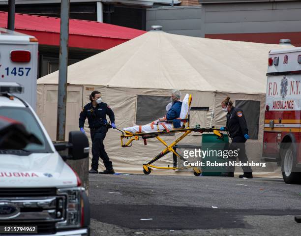 Two members of the Fire Department of New Yorks Emergency Medical Team wheel in a patient with potentially fatal coronavirus to the Elmhurst Hospital...