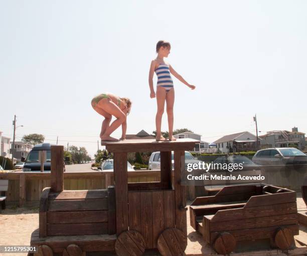 little girls playing on a toy train outside at a park at the beach wearing bathing suits. - long beach island stockfoto's en -beelden