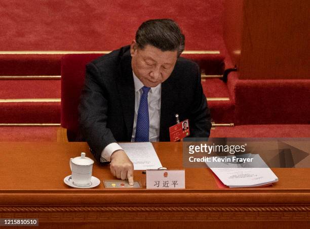 Chinese President Xi Jinping, presses the green button as he votes during the closing session of the National People's Congress at the Great Hall of...