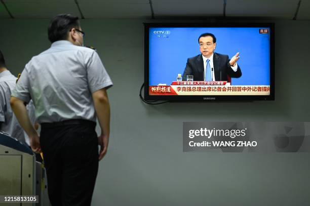 Staff member of subway station watches live coverage of China's Premier Li Keqiang speaking during a press conference in Beijing on May 28, 2020. -...