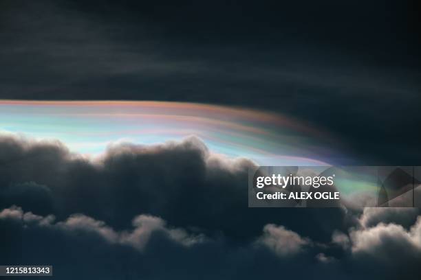 Cloud iridescence, an optical phenomenon where light is diffracted through water droplets, is pictured at the edge of clouds before a summer...