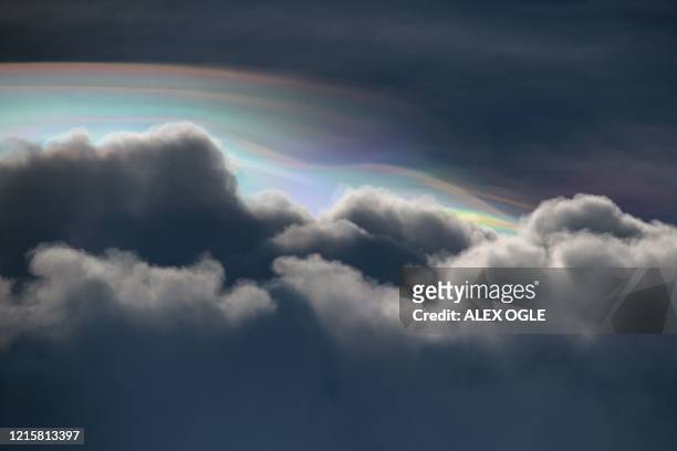 Cloud iridescence, an optical phenomenon where light is diffracted through water droplets, is pictured at the edge of clouds before a summer...