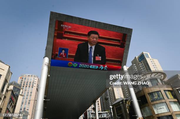 Outdoor screen shows live coverage of Chinas President Xi Jinping attending the closing session of the National Peoples Congress in Beijing on May...