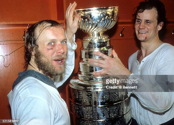Butch Goring and Stefan Persson of the New York Islanders celebrate with the Stanley Cup Trophy in the locker room after the Islanders defeated the...