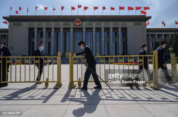 Chinese security officers wear protective masks as they close the gates after the closing session of the National People's Congress at the Great Hall...