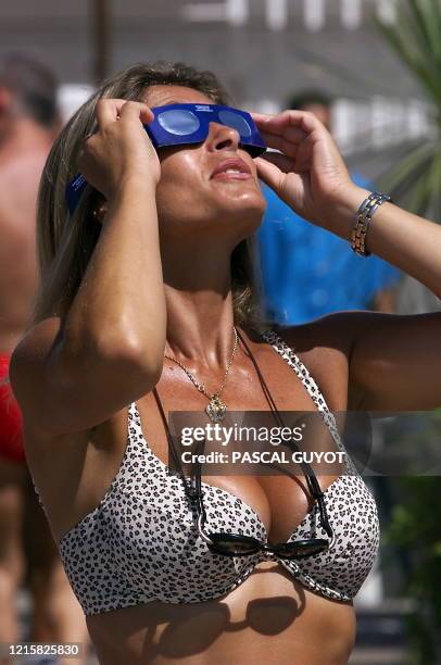 Une femme en maillot de bain observe l'éclipse solaire, le 11 août 1999 devant l'hôtel Negresco sur une plage de Nice, où de nombreux touristes sont...