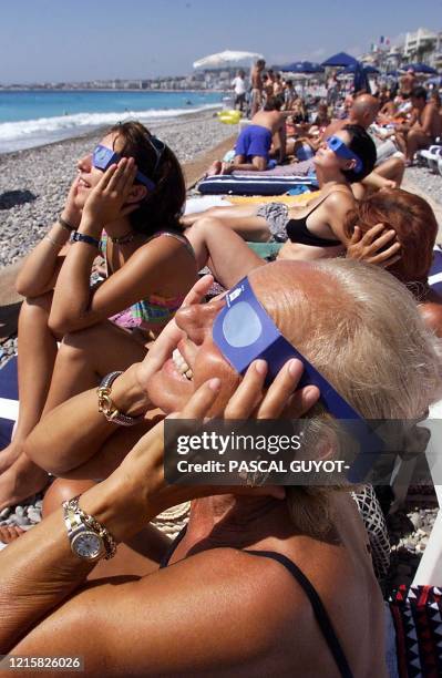 Des touristes italiennes observent l'éclipse solaire, le 11 août 1999 devant l'hôtel Negresco sur une plage de Nice, où de nombreux touristes sont...