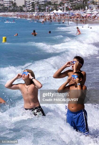 Des enfants en maillot de bain observent l'éclipse solaire, le 11 août 1999 sur une plage de Nice, où de nombreux touristes sont venus assister à la...