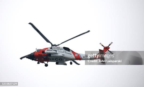 Coast Guard helicopter, seen from Pier 86, flies as the USNS Comfort hospital ship travels north on the Hudson River as it heads to Pier 90 on March...