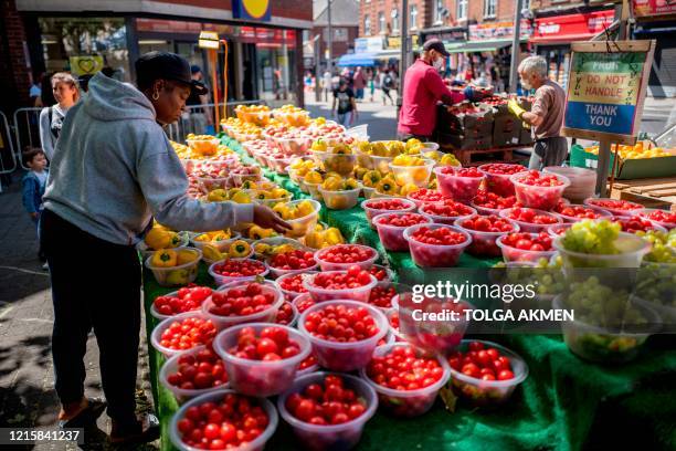 Shopper selects a bowl of yellow peppers as she shops at an outdoor street market in Walthamstow, east London on May 28 during the COVID-19 pandemic....