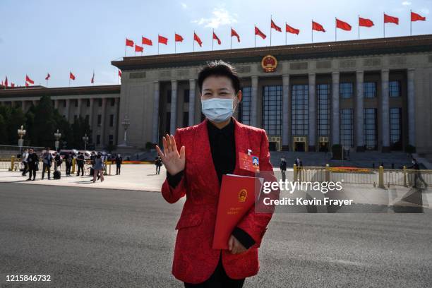 Communist Party delegate wears a protective mask as she gestures while leaving after the closing session of the National People's Congress at the...