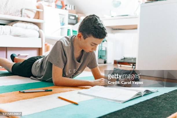 teenage boy doing homework and homeschooling during qurantine - compiti foto e immagini stock