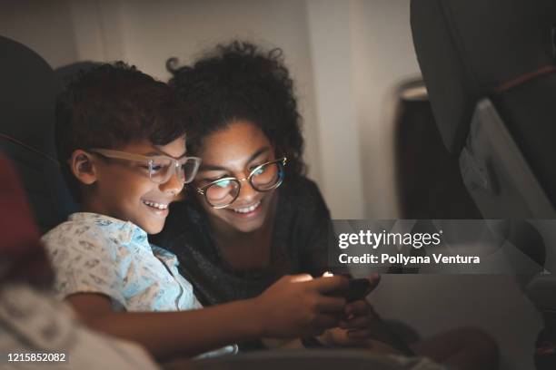 kinderen die slimme telefoon tijdens de vlucht gebruiken - familly glasses stockfoto's en -beelden