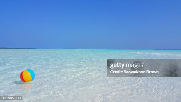 colorful beachball floating by sea flows washing white sandy beach of tropical island on a hot summer day, copy space - beach ball stock pictures, royalty-free photos & images