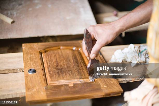 man in workroom paints varnish on a piece of wood - polishing stock pictures, royalty-free photos & images