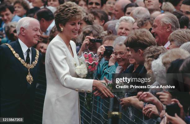 British royal Diana, Princess of Wales , wearing an ivory two-piece suit, greeting well-wishers who had gathered to see her during a visit to...