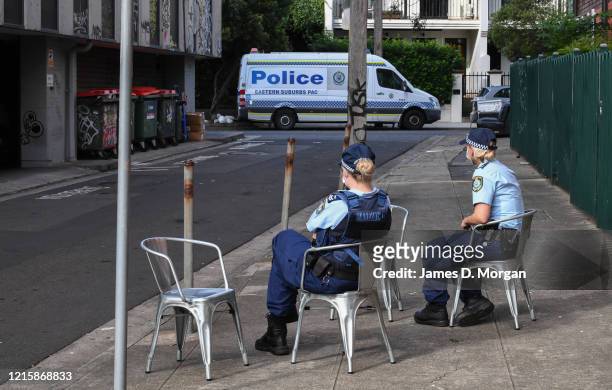 Police officers wearing face masks guard the rear entrance of the Urban Newtown hotel where quarantined Australian travellers who have landed back...