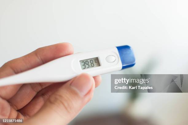 a young person is holding a thermometer with high temperature - digital thermometer stock pictures, royalty-free photos & images