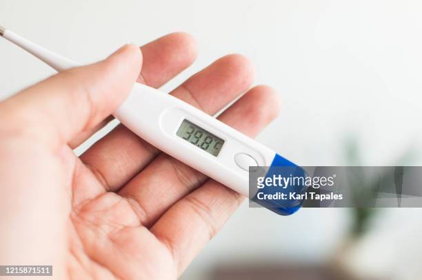 a young person is holding a thermometer with high temperature - febre imagens e fotografias de stock