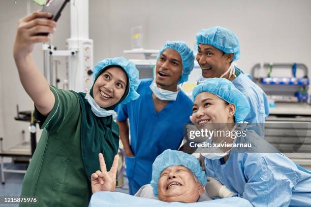 chirurgisch team en patiënt nemen selfie in operatiekamer - funny surgical masks stockfoto's en -beelden