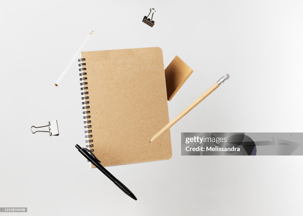 Stationery set. Levitation of notepad, pencils, pen, sticker and binder clips. Copy space on notebook and notes. Writing tools. Office supplies. Isolated on gray backdrop