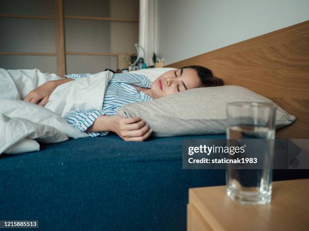 asian woman caught flu and drinking water in bed at home. - wake water stock pictures, royalty-free photos & images