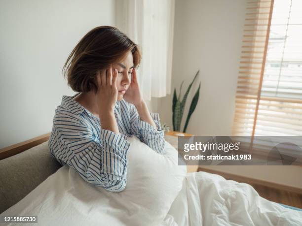 asian woman caught flu and drinking water in bed at home. - symptom stock pictures, royalty-free photos & images