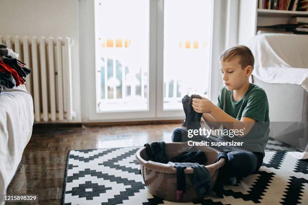 de jonge jongen vouwt kleren - geplooid stockfoto's en -beelden