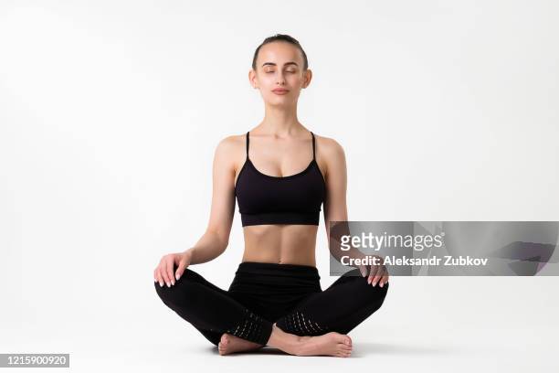 a young woman practices yoga in the lotus position, with her eyes closed - positionner photos et images de collection