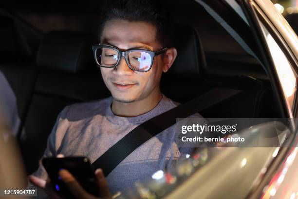 man using a smart phone in a car - asian man car stock pictures, royalty-free photos & images