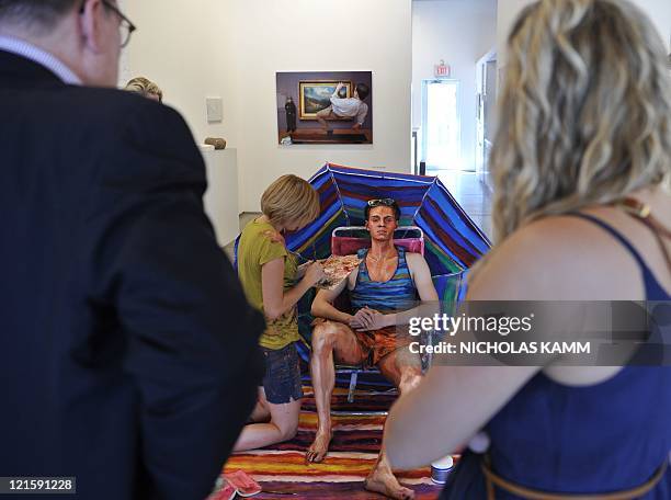 People watch US artist Alexa Meade paint model Will Claybaugh during a performance at the Irvine Contemporary gallery in Washington on August 20,...