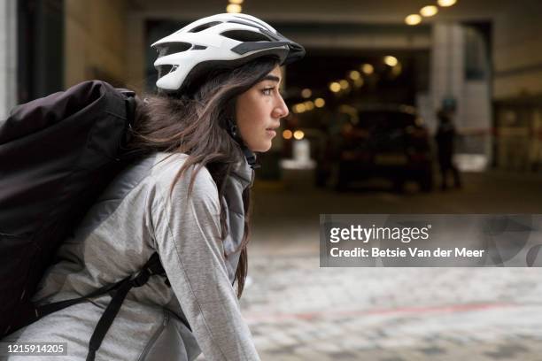 female courier is cycling to delivery destination. - london bikes stock pictures, royalty-free photos & images