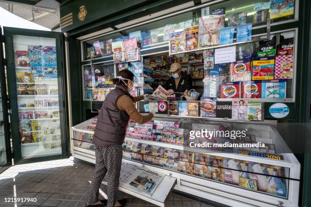 protected woman with a mask buys the press at a newsstand during the coronavirus pandemic. valencia, spain. - banca de jornais imagens e fotografias de stock