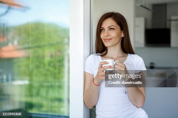 young woman enjoying coffee at home - coffee window stock pictures, royalty-free photos & images