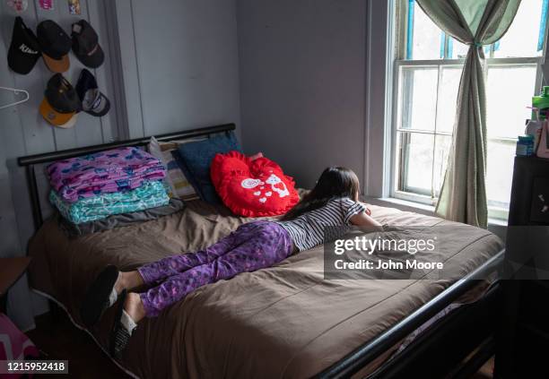 Honduran asylum seeker looks from her bedroom window during self-quarantine with her family for possible COVID-19 on March 30, 2020 in Mineola, New...