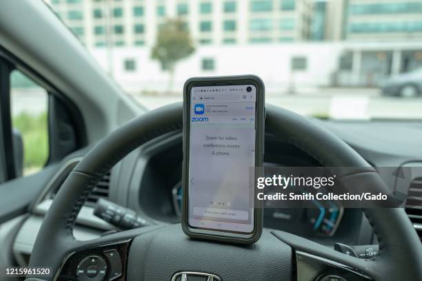 Remote work setup in automobile with cellphone showing Zoom and Chromebook laptop during COVID-19 coronavirus outbreak in San Francisco, California,...