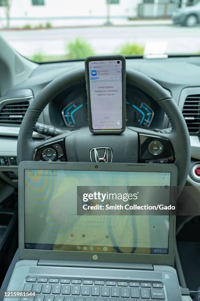 Remote work setup in automobile with cellphone showing Zoom and Chromebook laptop during COVID-19 coronavirus outbreak in San Francisco, California,...