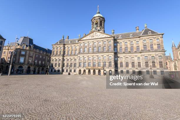 Almost deserted Dam square with the Royal Palace of Amsterdam in Amsterdam during a weekday morning following the advice of the Dutch government to...