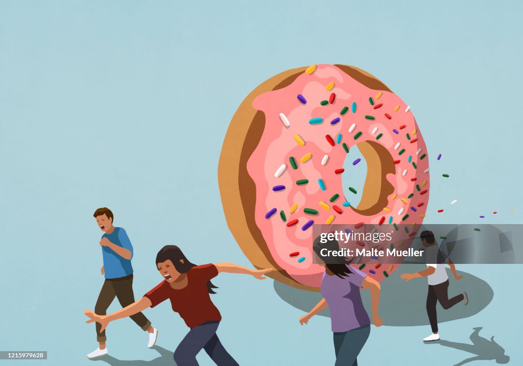 People running from large sprinkled donut