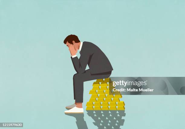 worried male investor sitting on stack of gold bars - 1 person planung stock-grafiken, -clipart, -cartoons und -symbole