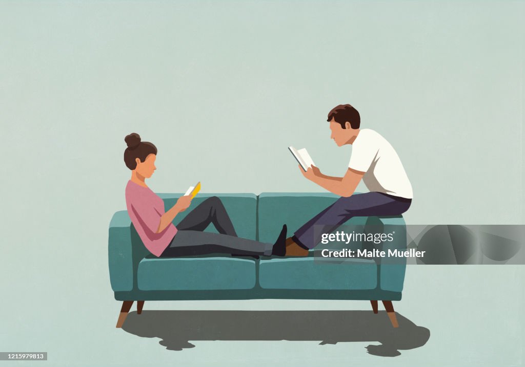Couple reading books on sofa