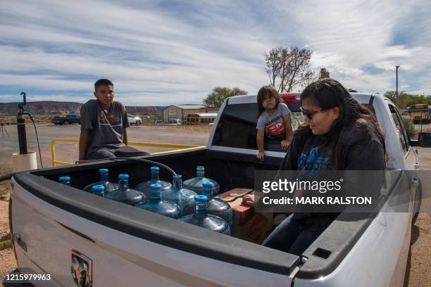 Members of the Larson family who have no running water in their home, collect water from a distribution point in the Navajo Nation town of Thoreau in...