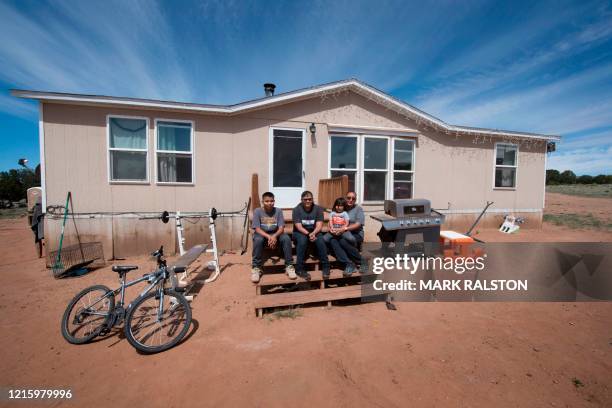 Members of the Larson family who have no running water, sit outside their home in the Navajo Nation town of Thoreau in New Mexico on May 22, 2020. -...