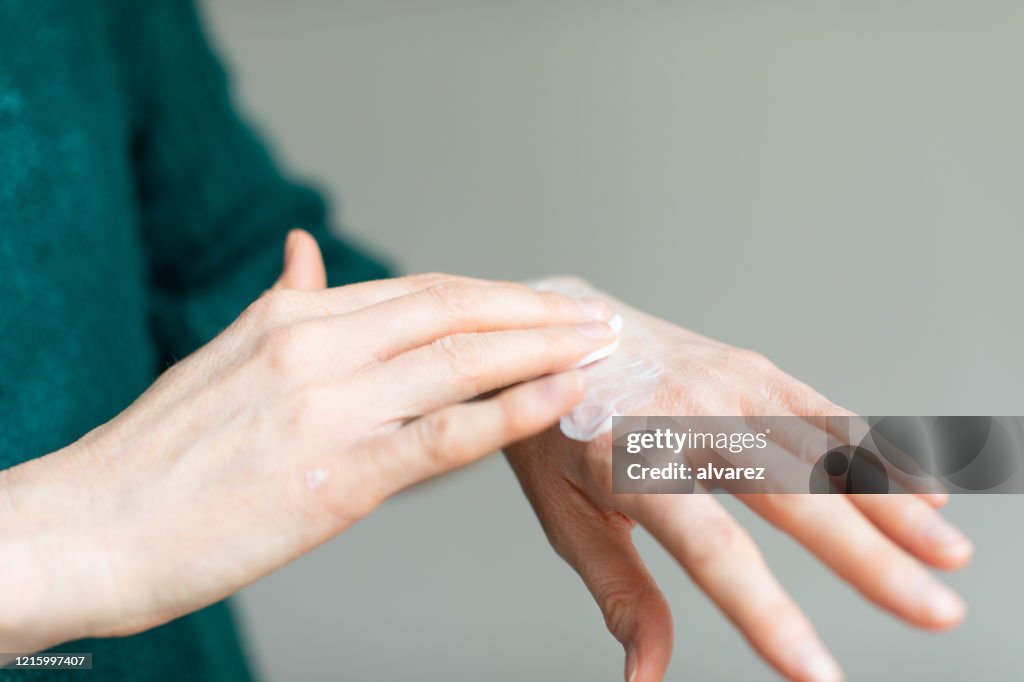 Woman applying hand cream to relieve the dry skin caused by hand sanitizer