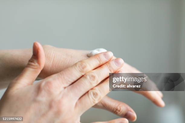 woman applying hand cream to relieve the dry skin caused by hand sanitizer - manicure set stock pictures, royalty-free photos & images