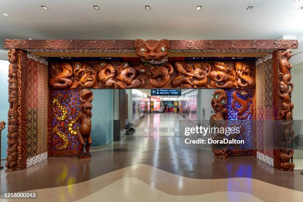 arrival entrance gate decorated with art carvings in auckland international airport terminal building, new zealand - auckland airport stock pictures, royalty-free photos & images