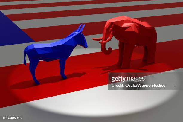 democratic blue donkey and republican red elephant in spotlight on top of american flag - politische partei stock-fotos und bilder