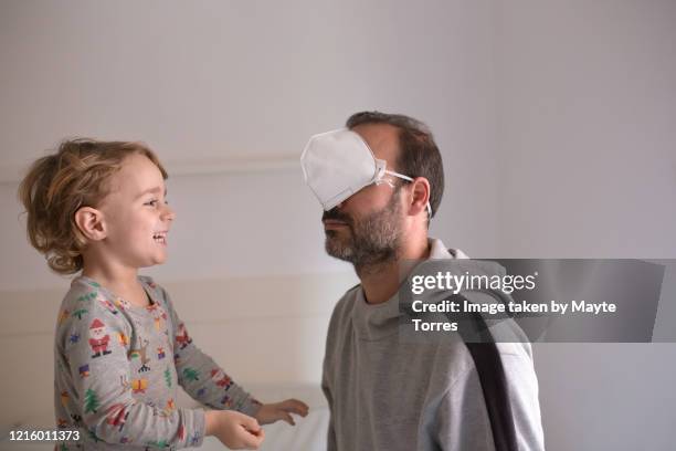boy laughing at dad after putting surgical mask in eyes - funny mistake stock pictures, royalty-free photos & images