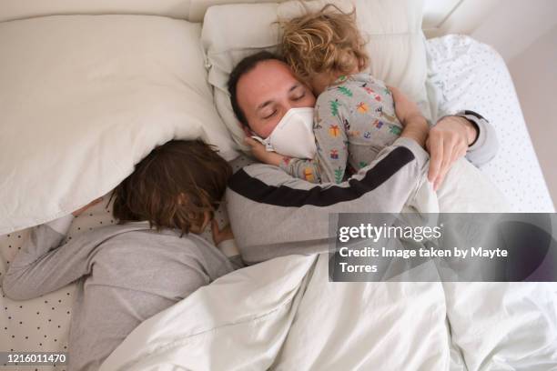 dad sleeping with surgical mask with two sons - sleep hygiene stock pictures, royalty-free photos & images