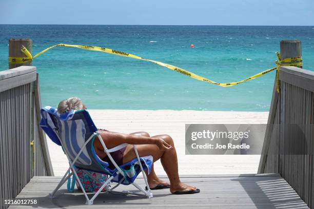 Linda Bodell, from Minnesota, takes in some sun on the walkway leading to the beach on March 31, 2020 in Hollywood, Florida. The City of Hollywood...